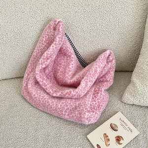 Detail of pink leopard plush tote bag with checkered lining on soft beige sofa