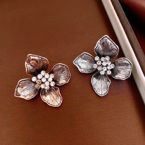 Macro detail of vintage floral brooches with brushed metal petals and crystal centers