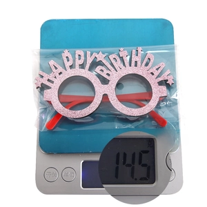 Close-up of pink Happy Birthday party glasses on a digital scale weighing 14.5g