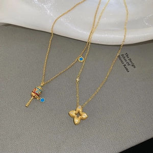 Detail of gold hollow flower and spinning cylinder pendant necklaces on a book