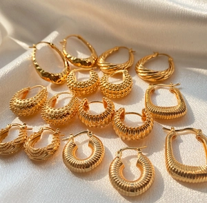 Detailed view of various 18K gold plated hoop earrings on elegant white silk fabric
