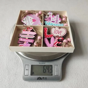 Set of pink wooden Valentine's Day ornaments in a 4-compartment tray being weighed