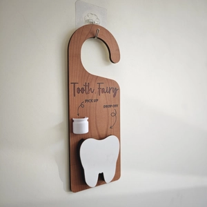 Close-up of wooden tooth fairy door hanger with pick-up cup and drop-off slot
