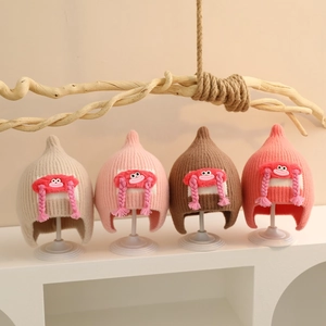 Detail view of winter baby knit hats with cartoon braid dolls in multiple colors