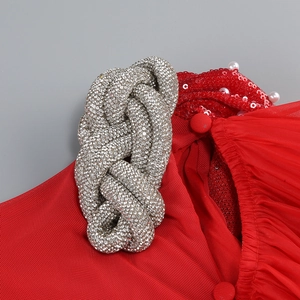 Détail de robe de soirée rouge avec nœuds en strass argentés, paillettes et perles