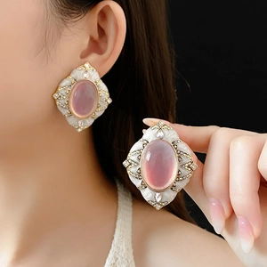 Detail of vintage oval pink stone earrings with white enamel and gold-plated borders