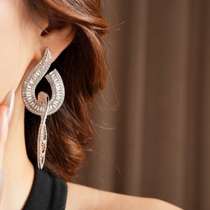 Close-up of geometric curved silver earrings with sparkling rectangular zircons on model