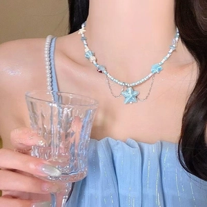 Detail of blue starfish pendant and bead necklace on model with silver drop chain