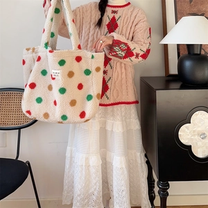 Close-up of beige plush tote bag with colorful polka dots and a white brand label detail