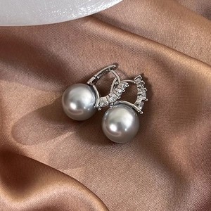 Macro detail of grey pearl hoop earrings with zircon accents on brown silk fabric