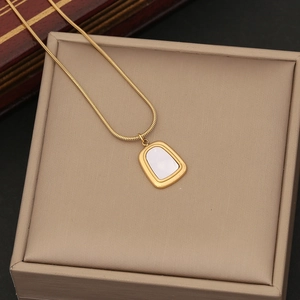 Golden geometric shell pendant on snake chain necklace displayed in a beige jewelry box