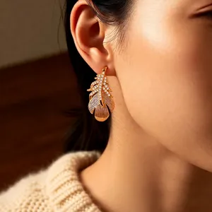 Elegant 18k gold plated feather earrings with cubic zirconia worn by a female model