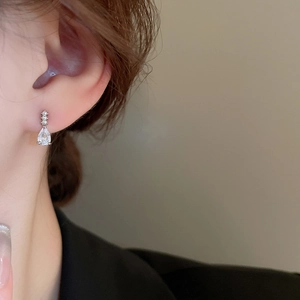 Gros plan détaillé de boucles d'oreilles goutte en zircon argenté sur l'oreille