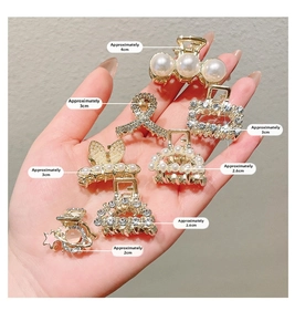 Detail showing various sizes of mini gold alloy hair clips with rhinestones and pearls