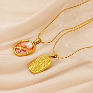 Detail of vintage gold necklace with starfish pearl pendant and hammered metal charm