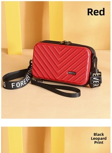 Detail of red hard shell crossbody bag with V-shaped texture and brand logo strap
