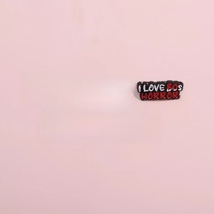 Five creative horror-themed enamel pins in red and black on a solid pink background