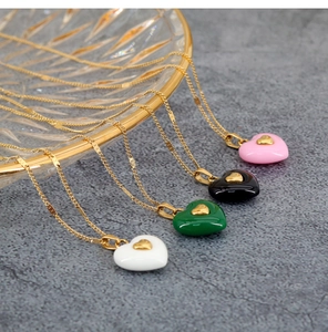 Detail showing various heart pendant necklaces in pink, black, green, and white colors