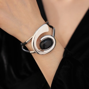 Detailed view of silver abstract bracelet with black gemstone on model wrist