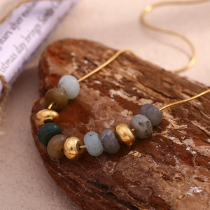 Détail d'un collier chaîne serpent plaqué or 18 carats avec pierres naturelles sur bois
