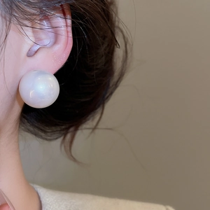 Macro view of large round pearl earring on model showcasing its elegant luster and size