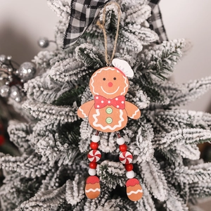 Detail of wooden gingerbread man ornament with dangling bead legs on a snowy tree