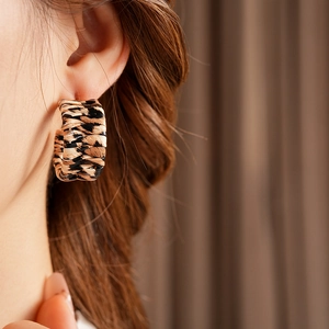 Close-up of leopard print woven leather C-shaped hoop earring worn by a model