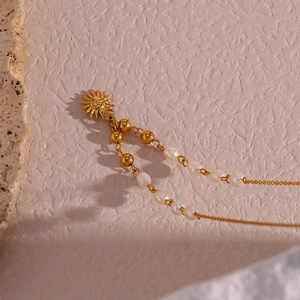 Golden sun pendant necklace featuring freshwater pearls and metallic beaded chain design