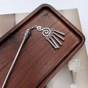 Macro detail of silver tassel hair pin with vintage Chinese fringe on a wooden tray