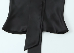Detail of the smooth black satin fabric texture and hem on a women's scarf shirt