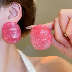 Close-up of oversized pink irregular oval earrings with brushed texture on model