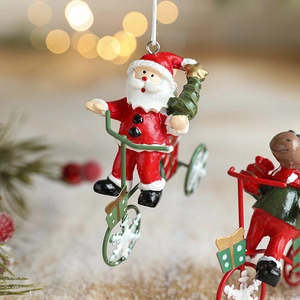 Resin Santa Claus riding a green bicycle ornament with festive warm bokeh background