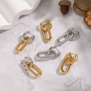 Two-tone 18K gold and silver stainless steel oval hoop earrings on marble surface