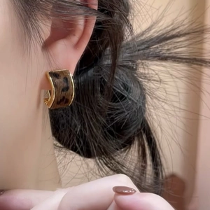 Close-up of leopard print C-shape hoop earrings worn by a model in a retro style