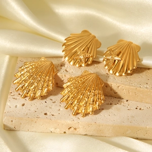 Detailed macro view of 18k gold shell and starfish earrings on elegant silk background