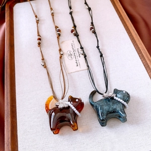 Detail showing resin cat pendants with pearl collars and flower charms on cord chains