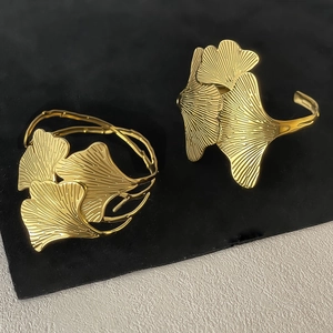 Detailed view of two golden ginkgo leaf napkin rings on a premium textured surface