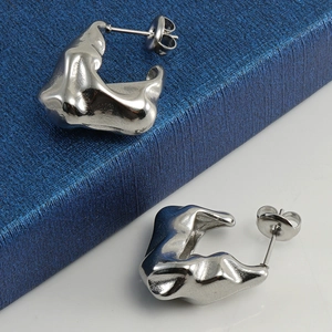 Dettaglio di orecchini stile metallo liquido irregolare in argento lucido su una scatola