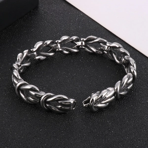 Macro view of twisted woven link stainless steel bracelet on black textured background