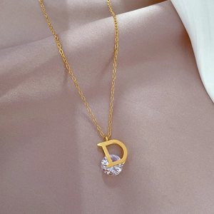 Macro shot of gold-plated titanium D-pendant necklace with zircon stone on satin