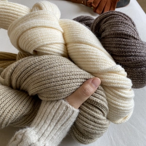Close-up of thick knit winter scarf showing soft texture in beige, camel, and brown