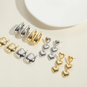 Detailed close-up of gold and silver U-shaped hoops and heart-shaped stud earrings