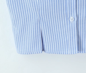 Macro shot of striped shirt hem detailing fine stitching and a white button accent