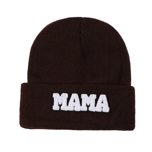 Close-up of white MAMA towel embroidery on a dark brown knit beanie with texture details