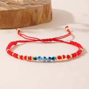 Détail du bracelet perles rouges avec l'œil maléfique et cordon tressé réglable