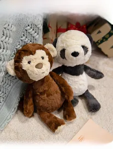 Close-up of soft plush monkey and panda toys on a cozy knitted blanket background
