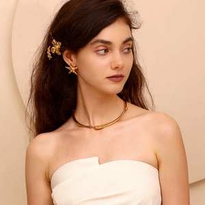 Close-up of golden starfish earrings and minimalist metal choker set on female model