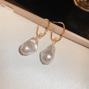 Close-up of golden U-shaped earrings featuring natural white baroque pearl pendants