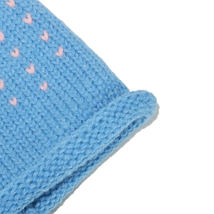 Détail de bonnet tricoté bleu avec motifs de cœurs roses et texture à bord roulé