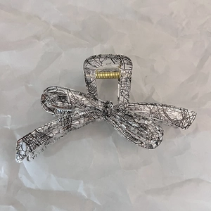 Detailed view of a transparent butterfly hair claw clip with black abstract patterns